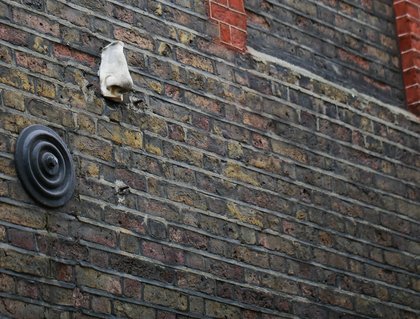 A plaster nose set into a painted brick wall in Soho, at about head height