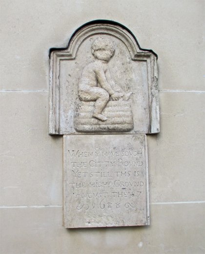 The Panyer Boy, a worn stone relief of a boy seated on a basket, set into a wall in Panyer Alley