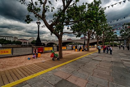 Waterloo Bridge seen from the South Bank walkway, its shallow concrete spans crossing to the Victoria Embankment with the city behind