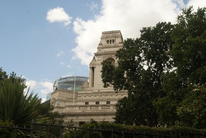 Trinity House on Trinity Square seen through the plane trees of the garden, its pale classical front rising above the railings