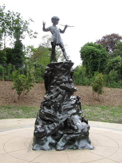 The Peter Pan statue in Kensington Gardens, the boy playing his pipes on a bronze base modelled as a tree stump crowded with small animals