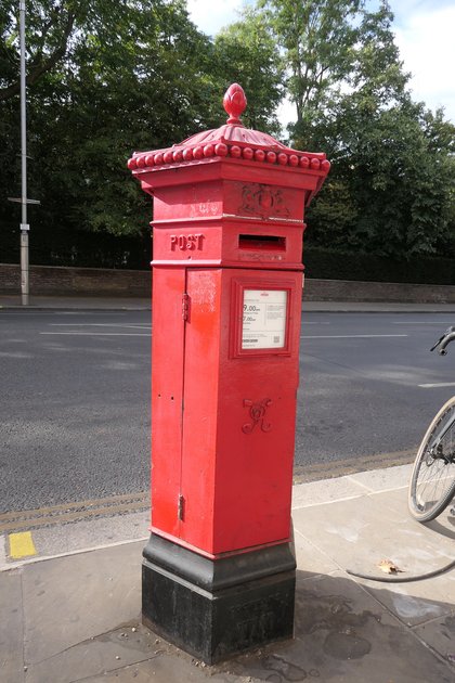 A Victorian Penfold pillar box in Kensington, hexagonal and fluted with an acanthus cap