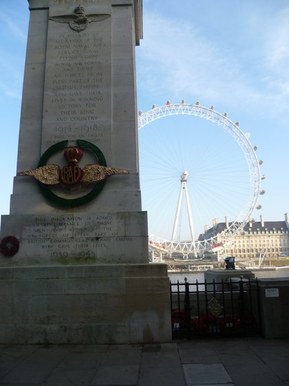 The Portland stone pylon of the Royal Air Force Memorial on Victoria Embankment, a wreath laid at its foot and the London Eye across the river