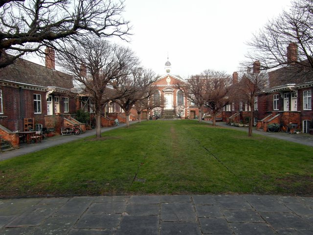 The central green at Trinity Green almshouses, two low brick terraces of 1695 facing each other across grass, the chapel and its cupola closing the view